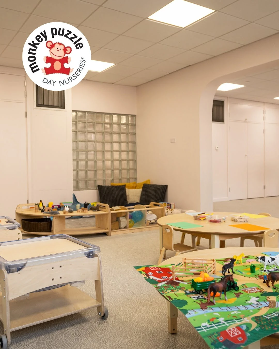 Nursery activity tables and a low wash area beside a glass-block window
