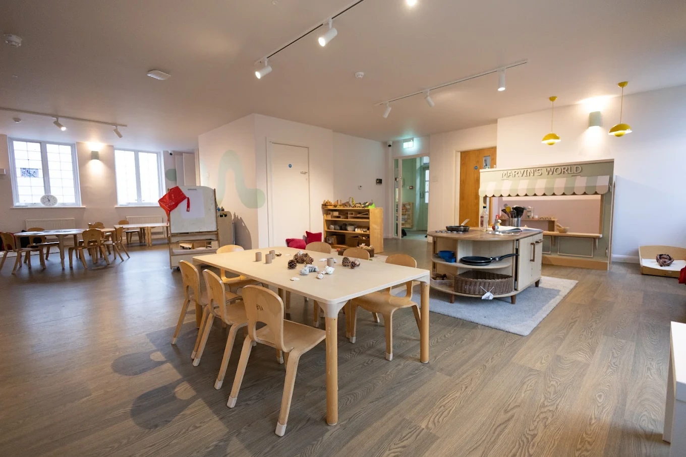 Ealing nursery activity room with low timber tables, storage and a painted wall detail
