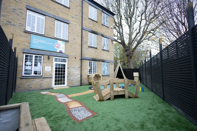 Ealing nursery garden with a winding path and the brick building beyond