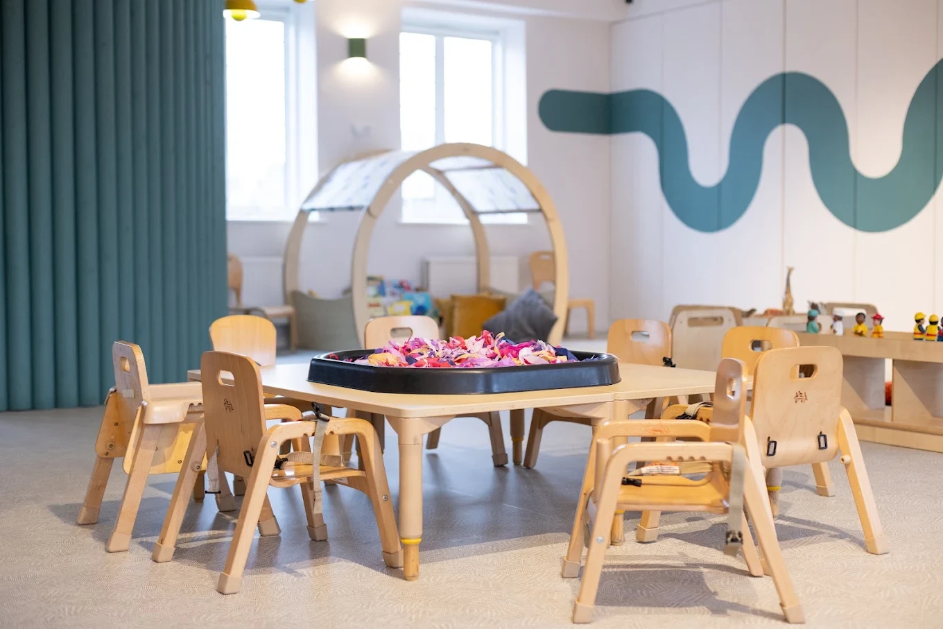 Child-height table and timber play frame beside a teal wall at Ealing