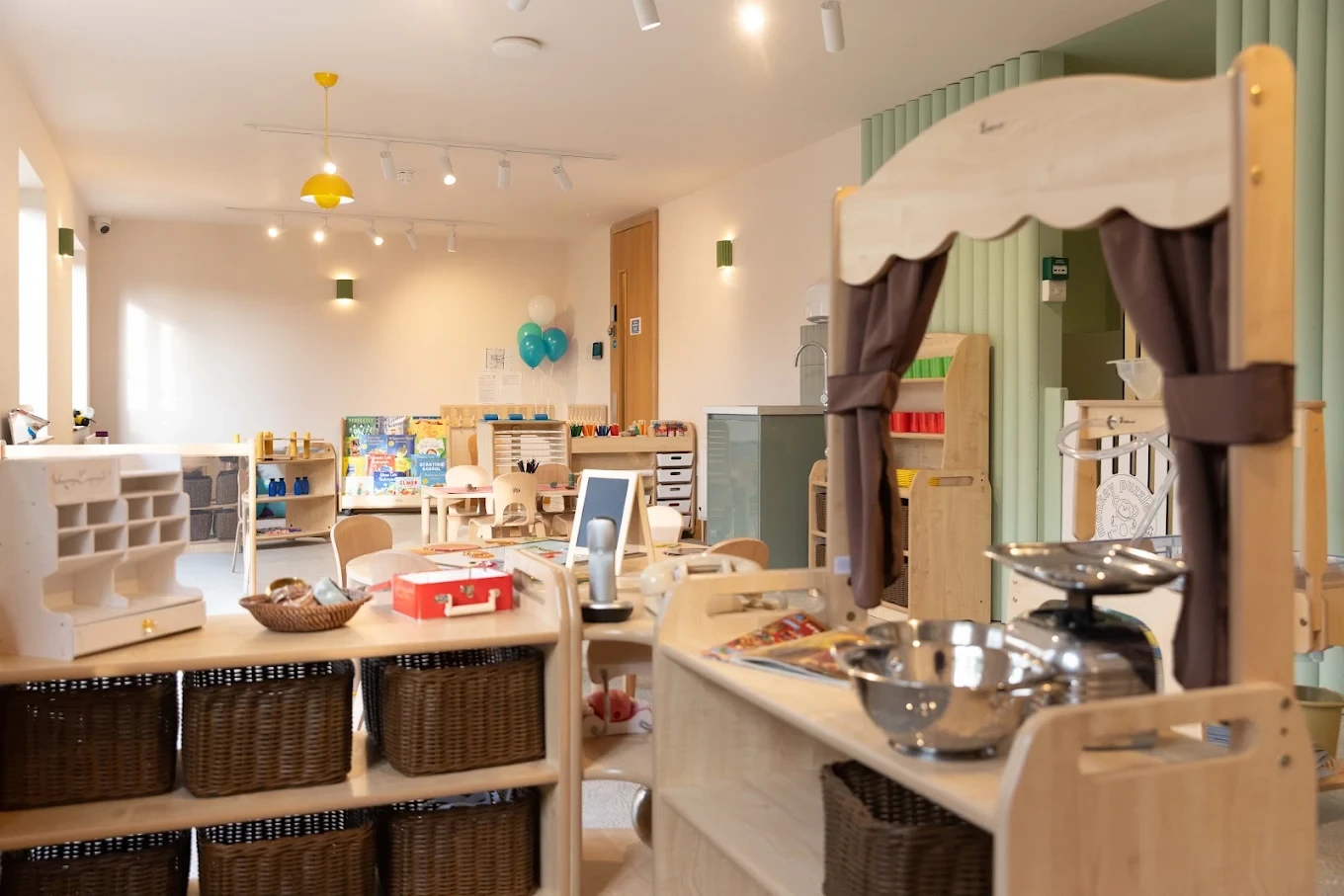 Timber play kitchen and small activity tables in a nursery room