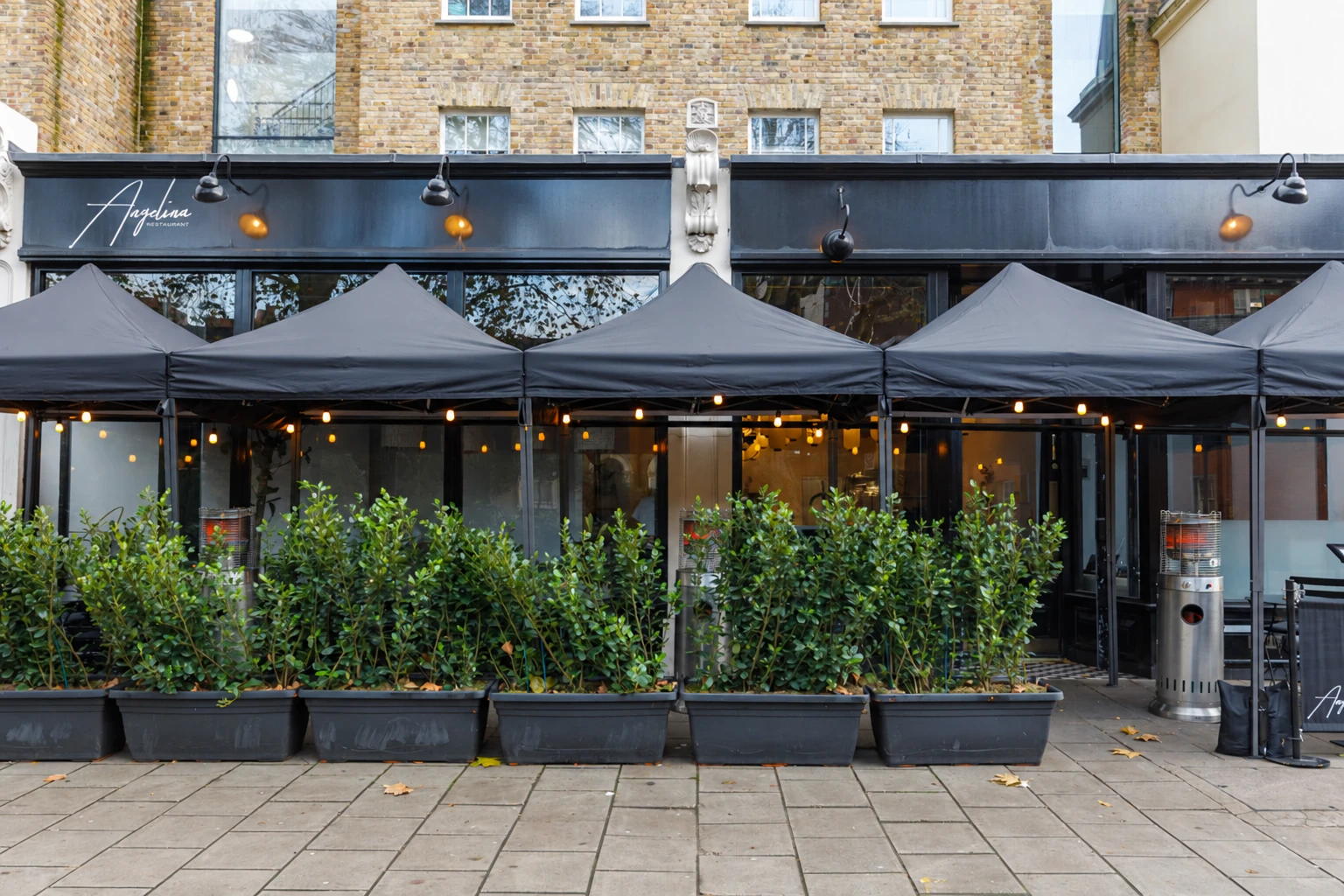 Angelina restaurant frontage on Dalston Lane with dark awnings and planted terrace